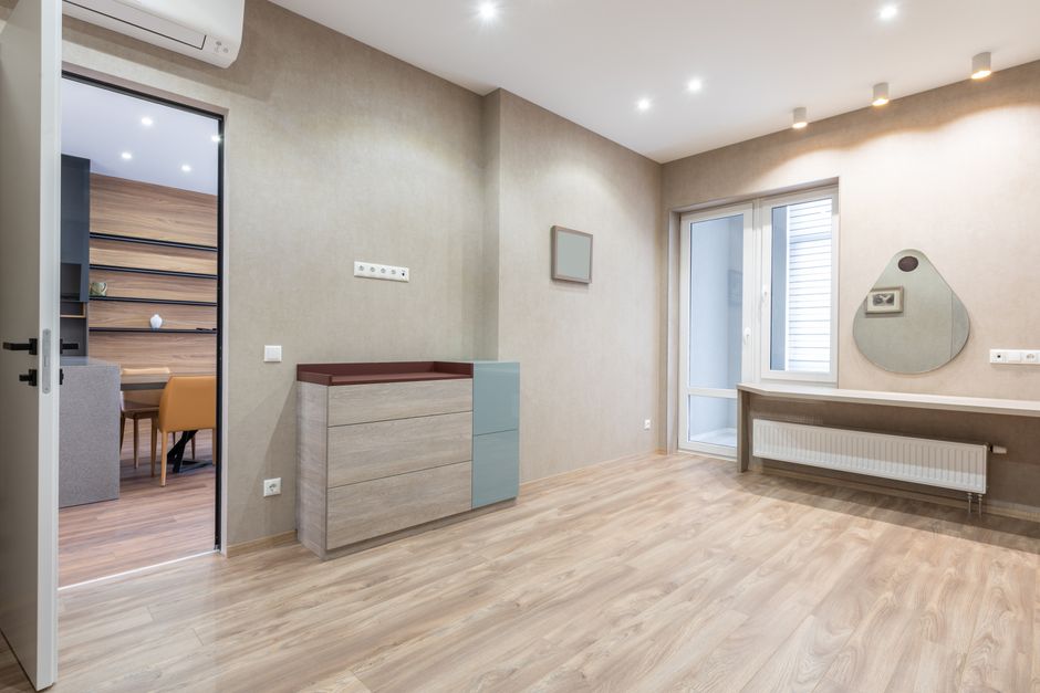 Interior of spacious light room with opened door and cupboard placed near glass entrance door in modern apartment with mirrors